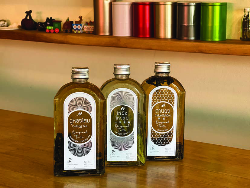 ขวด Cold Brew Tea สามขวดวางอยู่บนชั้นไม้ในร้าน
